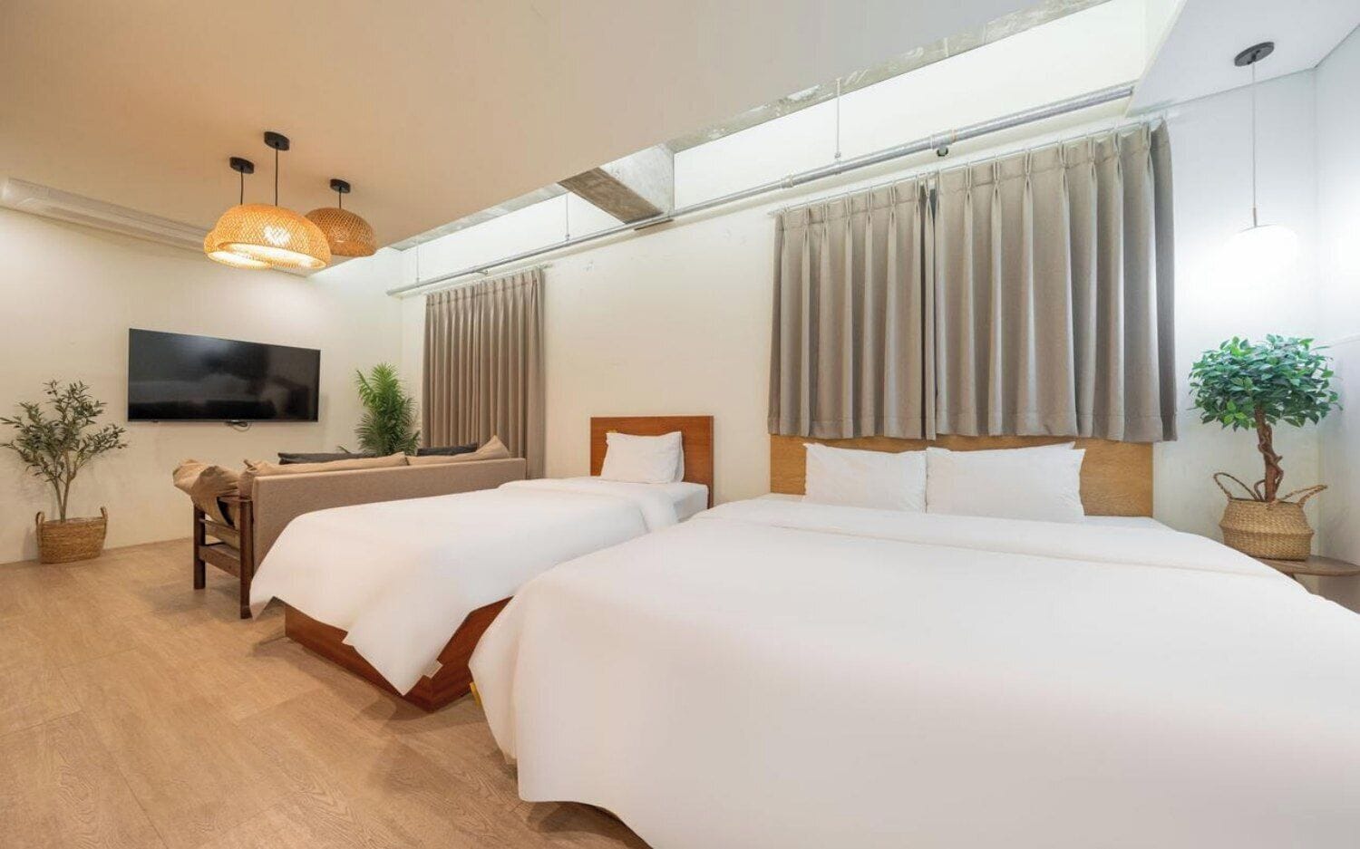 Habitación de hotel con dos camas, un televisor y un amplio ventanal con cortinas.