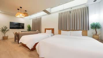 Habitación de hotel con dos camas, un televisor y un amplio ventanal con cortinas.