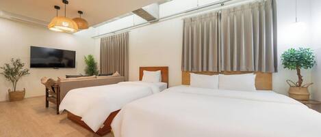 A hotel room with two beds, a TV, and a large window with curtains.