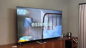 Ein Fernseher auf einem Holztisch mit Fernbedienung, einem Buch und einer Lampe.