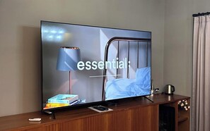 A television on a wooden stand with a remote control, a book, and a lamp. - alicehotel (Suwon)