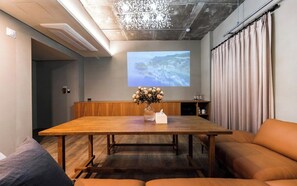 A conference room with a wooden table, a projector screen, a vase with flowers, and a sofa. - alicehotel (Suwon)