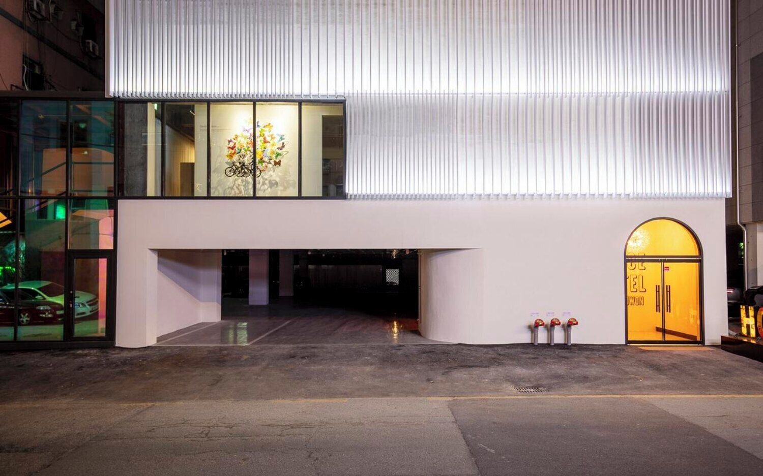 Un edificio moderno con fachada de vidrio, una entrada espaciosa y una puerta amarilla.