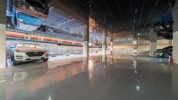 Un amplio estacionamiento interior con piso pulido, varios automóviles y un diseño moderno de techo.