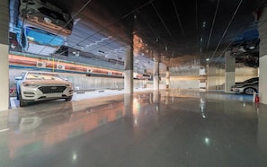 Un amplio estacionamiento interior con piso pulido, varios automóviles y un diseño moderno de techo.