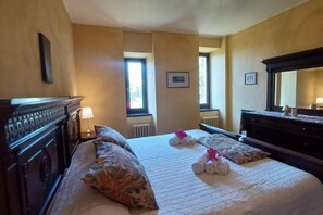 Ein Hotelzimmer mit einem großen Bett, einem Schminktisch, einem Spiegel und einem Fenster mit Tageslicht.