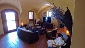 Una sala de estar acogedora con un sofá, sillones, una mesa de centro y un televisor.