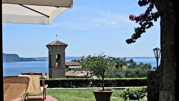 Un patio con vista al mar, una pequeña torre y una planta en maceta.