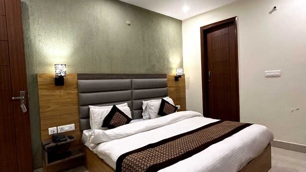 Een moderne slaapkamer met een groot bed, een houten hoofdbord, twee nachtkastjes, een plafondventilator en een deur.