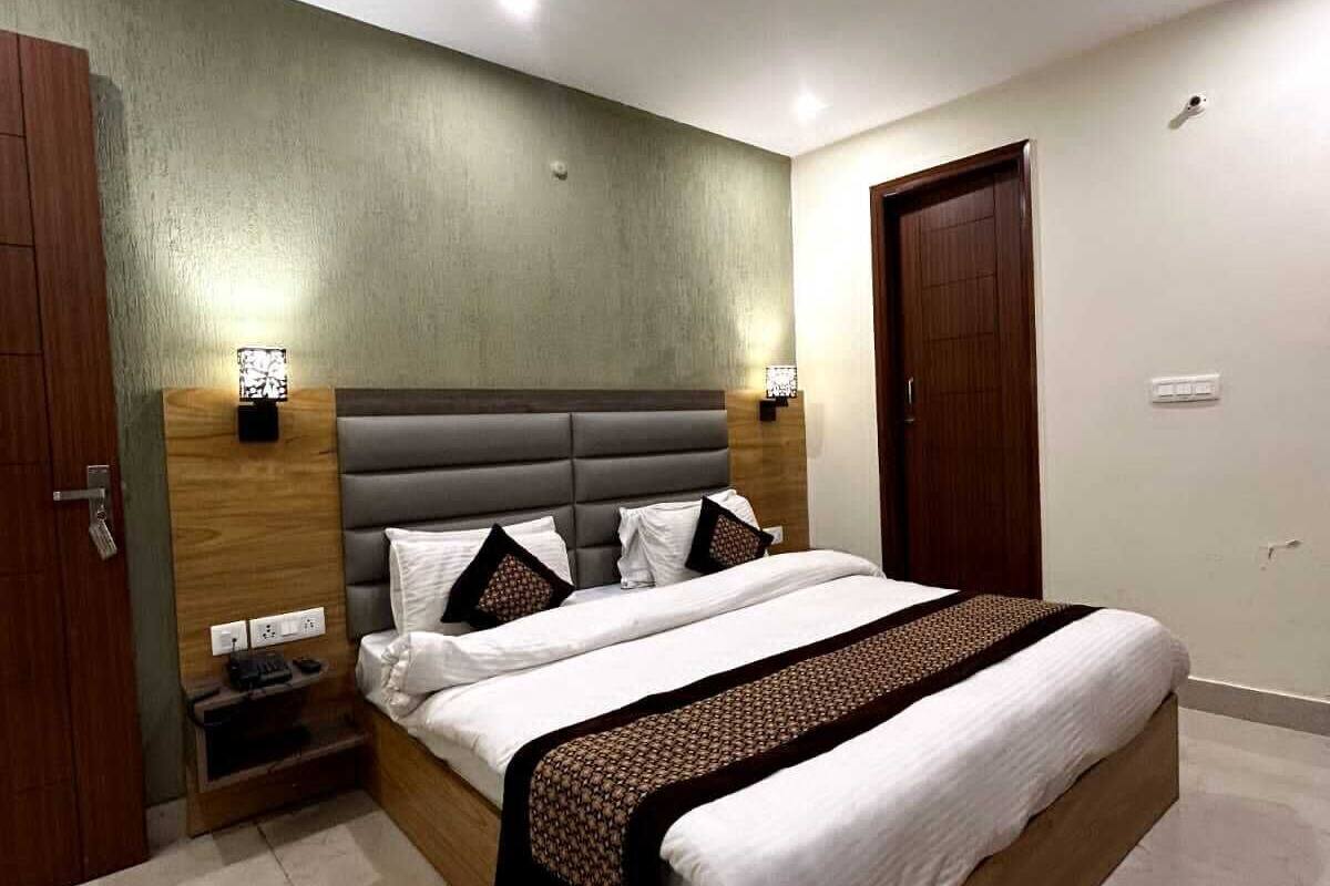 A modern bedroom with a large bed, wooden headboard, two bedside tables, a ceiling fan, and a door.
