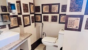 Een badkamer met een wastafel, toilet en douche. De wanden zijn betegeld met decoratieve tegels.