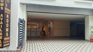 Een hotelentree met een betegelde vloer, een bord waarop staat dat kamers beschikbaar zijn, en een persoon die naar binnen loopt.