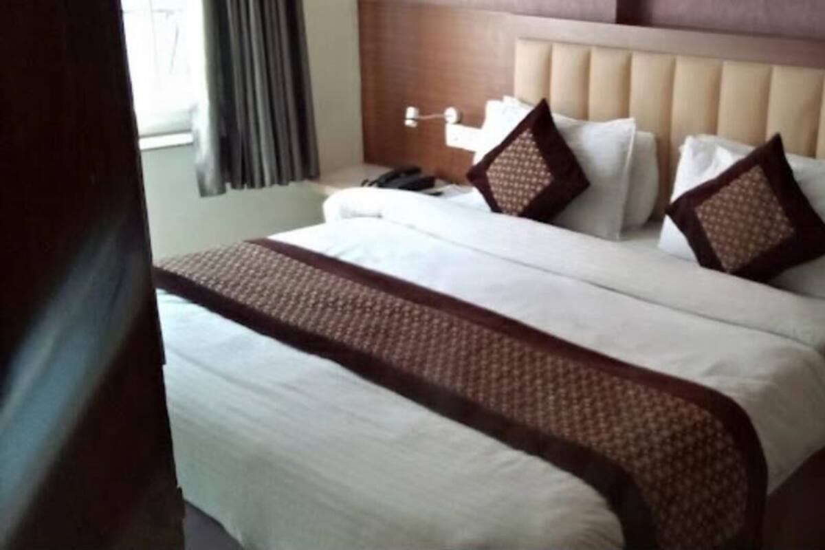 A hotel room with a large bed, a headboard, and a bedside table.