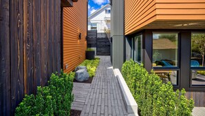 A modern building with a wooden exterior, a brick pathway, and green hedges. - Secret Hideaway - New Custom Built Home (Seattle)
