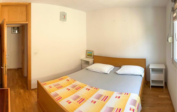 Un dormitorio con una cama, dos mesitas de noche, un tocador, un armario de madera y una ventana con persianas.