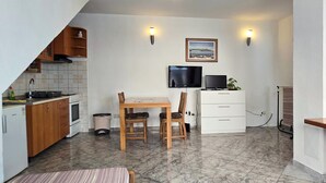 A compact kitchen with a dining area, a TV, and a small cabinet.