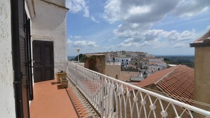 Un balcon doté d’une balustrade blanche, d’où l’on peut admirer une ville aux toits de tuiles rouges.