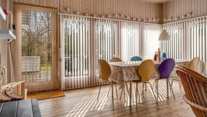 A wooden-paneled room with a dining table and chairs, a sofa, and a window with vertical blinds. - "Iris" - 200m to the fjord by Interhome (Thyholm)