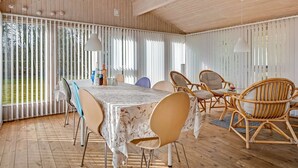 A covered outdoor dining area with a table and chairs, wooden flooring, and vertical blinds. - "Iris" - 200m to the fjord by Interhome (Thyholm)