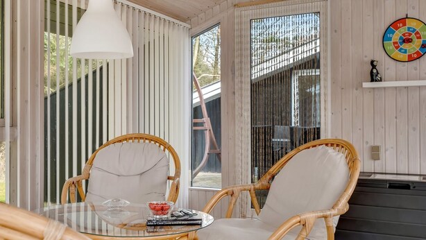 A cozy room with wicker chairs, a glass table, and a dartboard on the wall. - "Iris" - 200m to the fjord by Interhome (Thyholm)