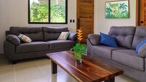 A living room with two grey sofas, a wooden coffee table, and a potted plant. - Villa Bruno - Terrace - Jungle - Birdwatching (Puerto Jiménez)