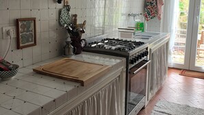 A kitchen with a gas stove, a wooden cutting board, and a tiled backsplash. - Detached house in the middle of the Tuscan chestnut forest (Arcidosso)