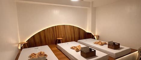 Una habitación con tres camas dispuestas en fila, un ventilador de techo y un aire acondicionado instalado en la pared.