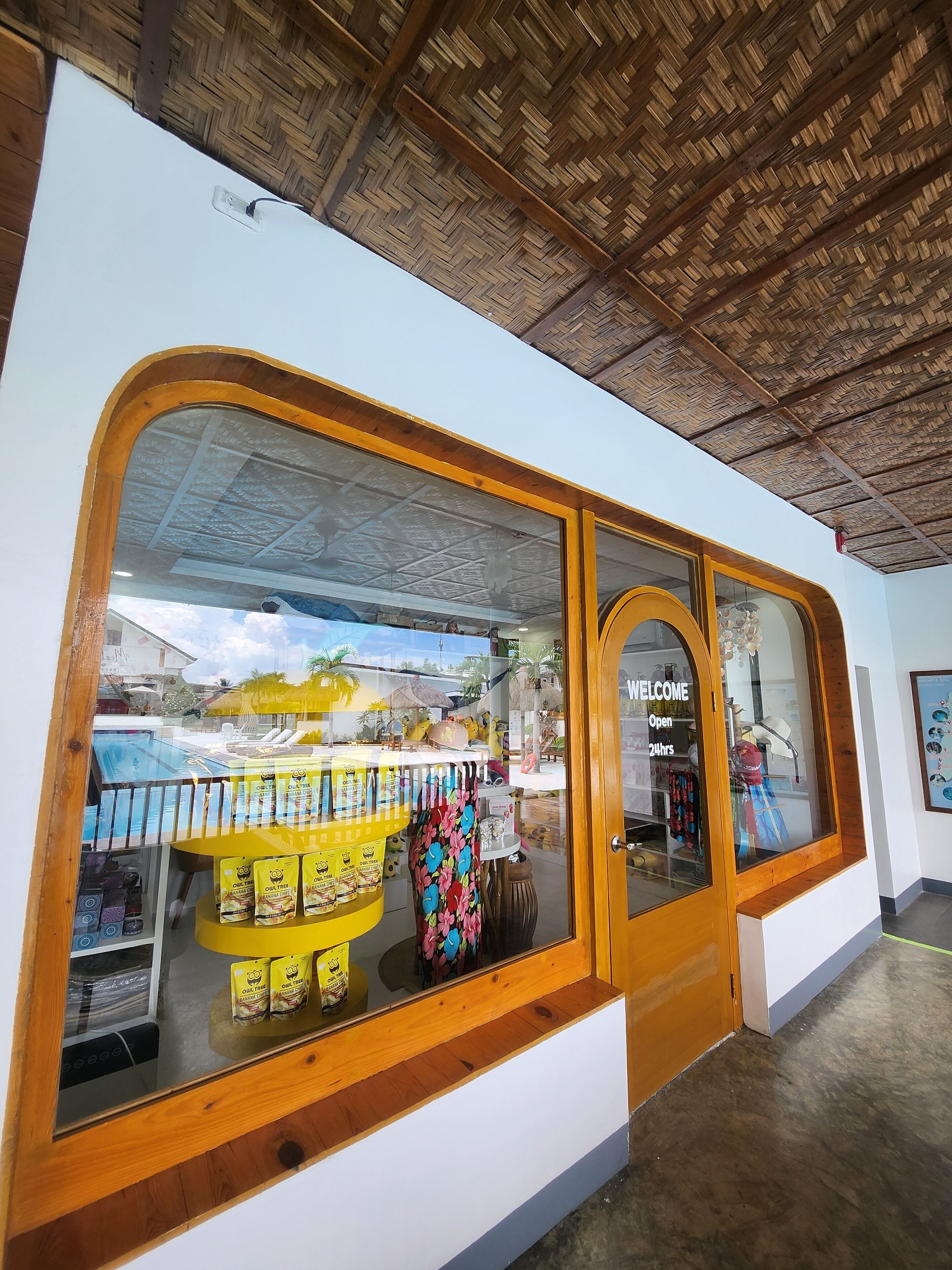 A storefront with a large display window, a wooden door, and a thatched roof ceiling.