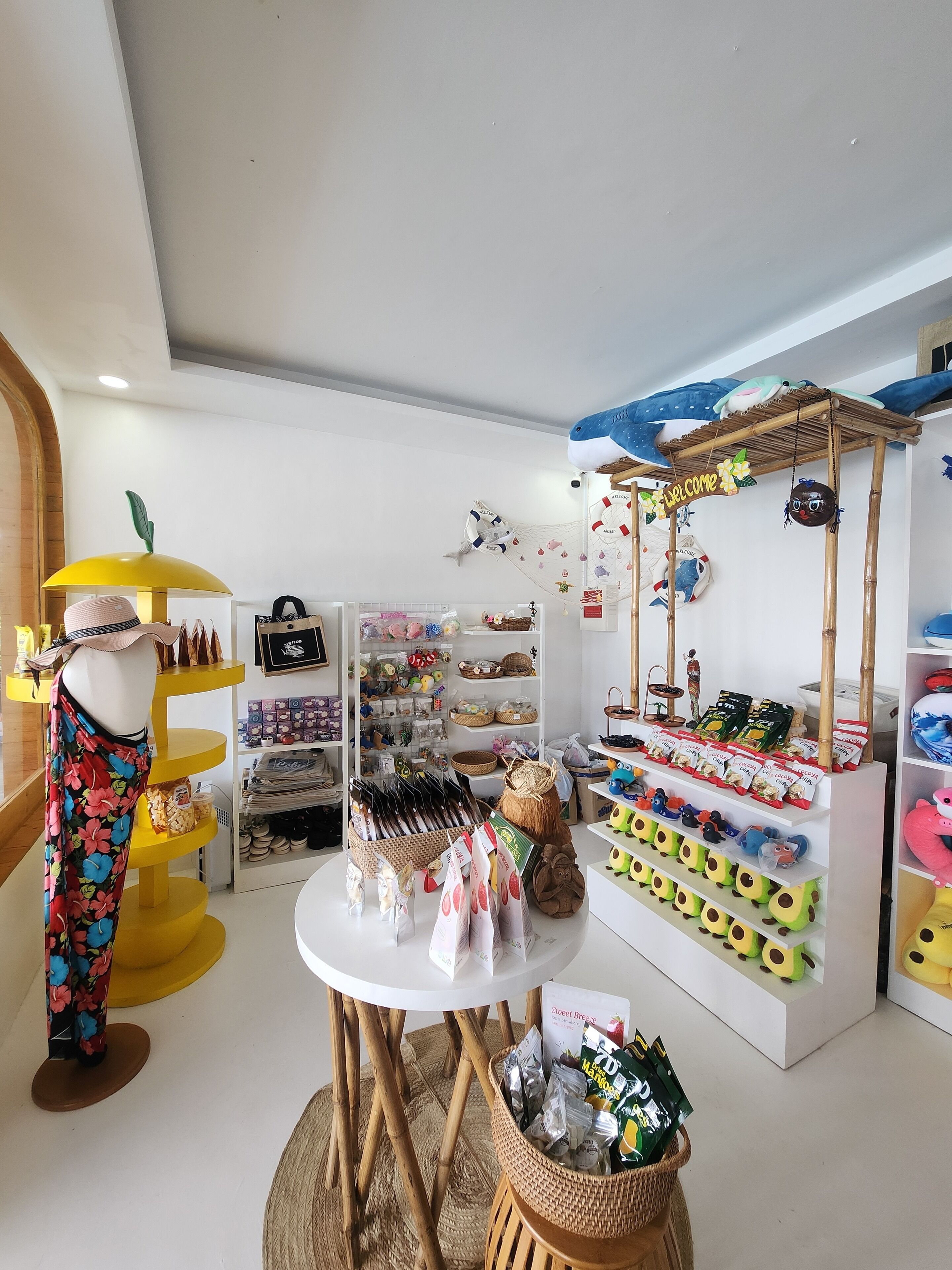 A boutique store with a mannequin, shelves of products, and a 'Welcome' sign.