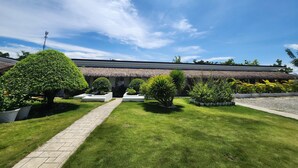 A well-maintained garden with a pathway leading to a building with a thatched roof.