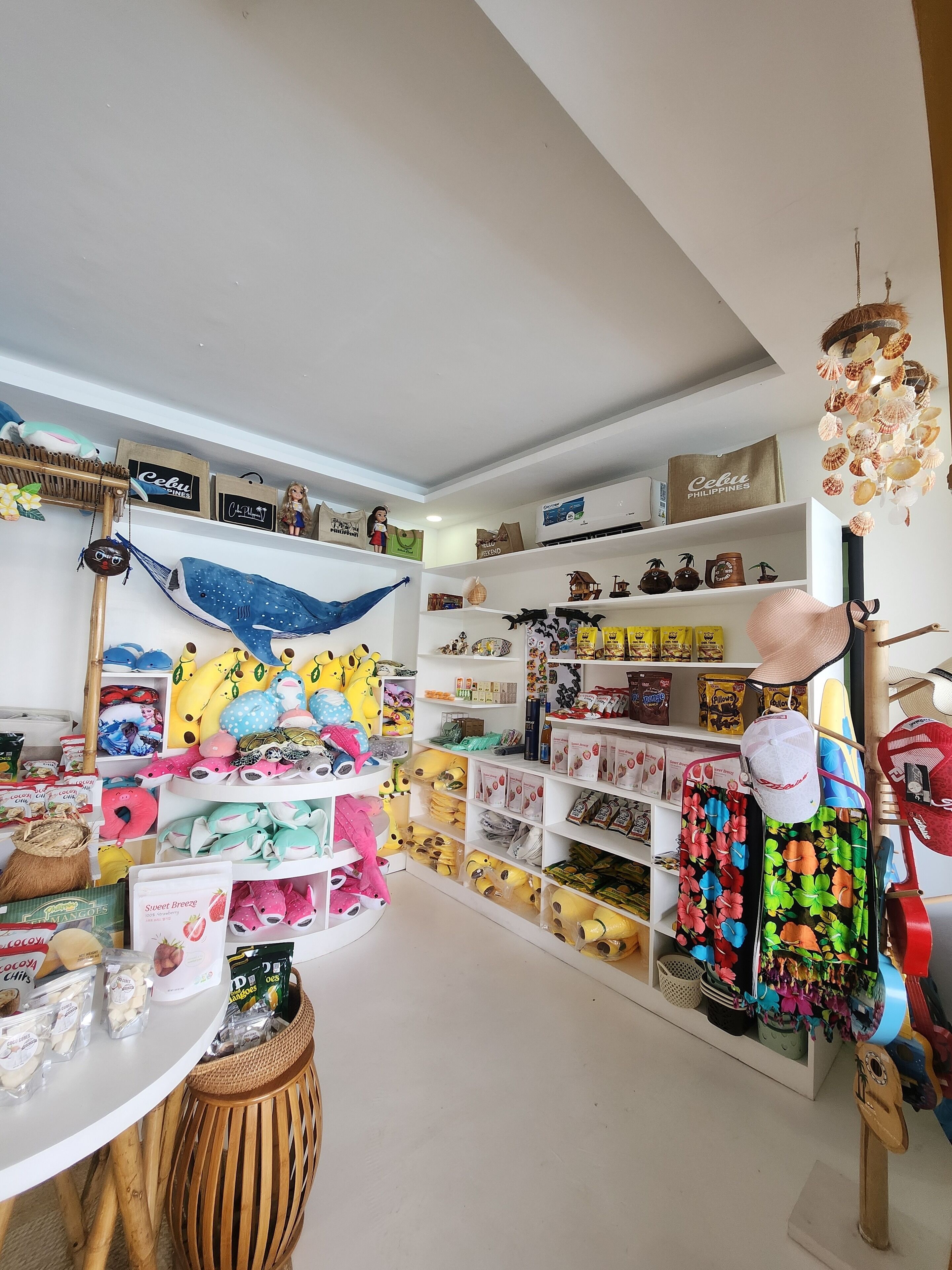 Una tienda bien organizada con estantes llenos de diversos artículos, incluyendo peluches, productos para el hogar y objetos decorativos.