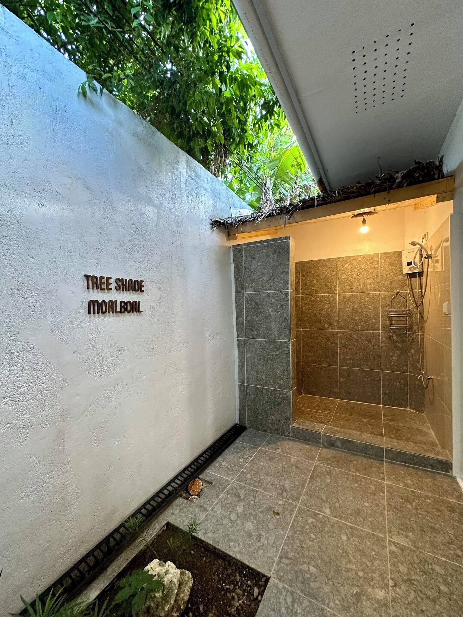 Un baño moderno con ducha, un lavamanos pequeño y un inodoro de pared.