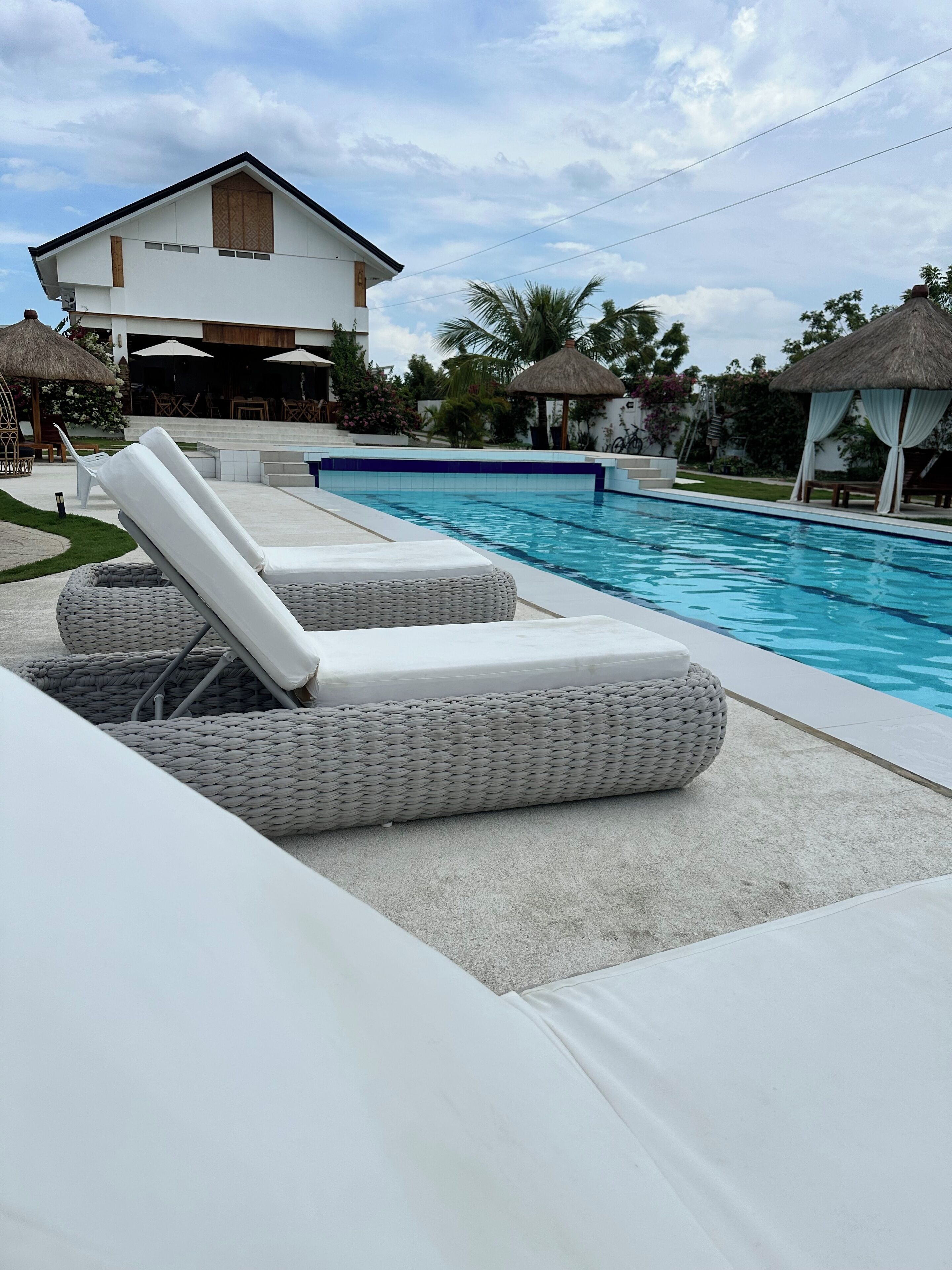 Zona de piscina con sillas de descanso y un edificio al fondo.