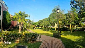 A pathway leading through a well-maintained garden with palm trees and a brick walkway. - Apartment 2 bedrooms • Pool View • Prado Golf • DAR01 (Isla Canela)