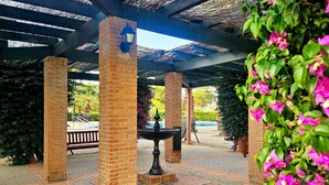 A covered outdoor area with brick pillars, a bench, and a fountain. - Apartment 2 bedrooms • Pool View • Prado Golf • DAR01 (Isla Canela)