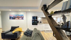 A modern living room with a grey sofa, a wooden coffee table, and a kitchen in the background. - Charming apartment 5P (Cauterets)