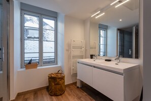 A modern bathroom with a large window, a white sink, and a mirror.