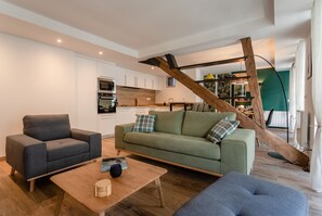 A modern living room with a sofa, a coffee table, and a staircase. - Charming apartment 5P (Cauterets)
