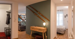 A modern living space with a wooden desk, a lamp, and a bed with a patterned bedspread. - Charming apartment 5P (Cauterets)