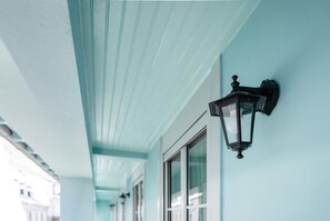 A corridor with a light blue wall and a black wall-mounted lantern. - Charming apartment 5P (Cauterets)