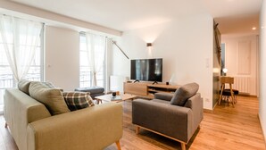 A modern living room with a flat-screen TV, two sofas, a coffee table, and a wooden floor. - Charming apartment 5P (Cauterets)