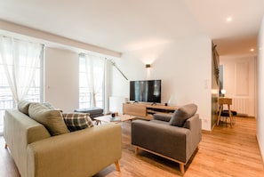 Ein modernes Wohnzimmer mit Flachbildfernseher, zwei Sofas, einem Couchtisch und Holzboden.