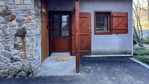 A stone house with a wooden door, a small porch, and a window with shutters.