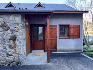 A stone house with a wooden door, a small porch, and a window with shutters. - Joli duplex 5P. Parking & balcon (Cauterets)