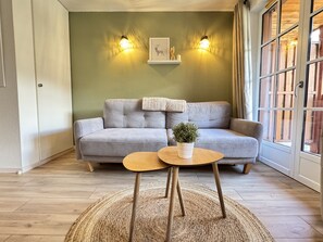A living room with a grey sofa, two wall-mounted lights, a framed picture, and a small table with a plant. - Joli duplex 5P. Parking & balcon (Cauterets)