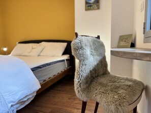 Une pièce avec un lit, un fauteuil moelleux et un plancher en bois.