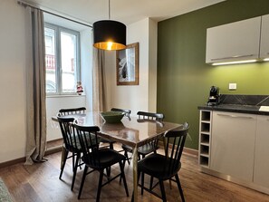 A dining area with a wooden table, black chairs, a green bowl, and a pendant light.