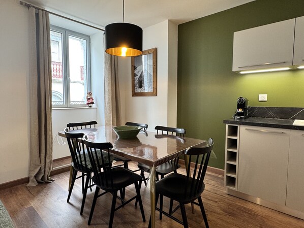 A dining area with a wooden table, black chairs, a green bowl, and a pendant light.