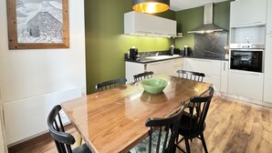 Una cocina moderna con armarios blancos, una mesa de comedor de madera y una lámpara colgante.