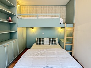 Une chambre avec un lit superposé, une échelle, une armoire et une étagère sur laquelle est posée une figurine de cochon.